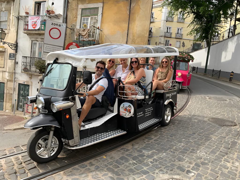 Guests on a private electric tuk tuk tour on a cobbled Lisbon street