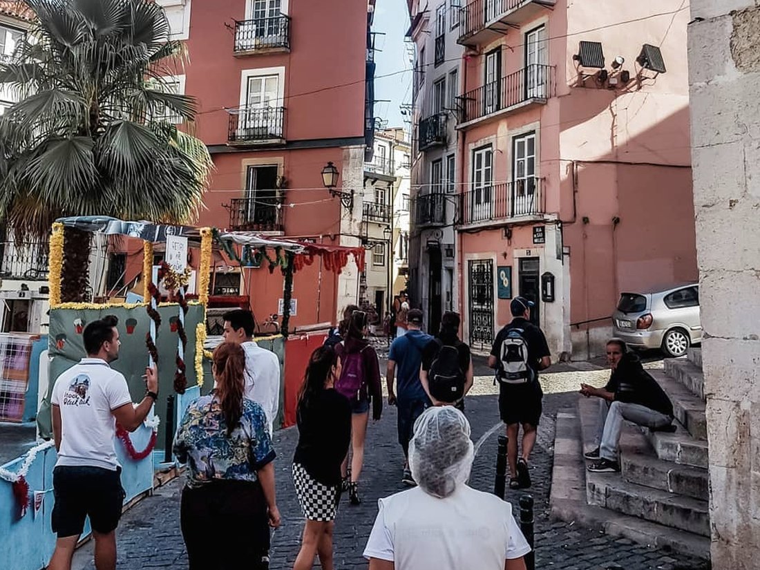 A busy Alfama street with market stalls and people walking