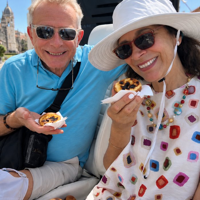 Two guests eating pastéis de nata in an I Took a Tuk Tuk electric tuk tuk outside the Jerónimos Monastery