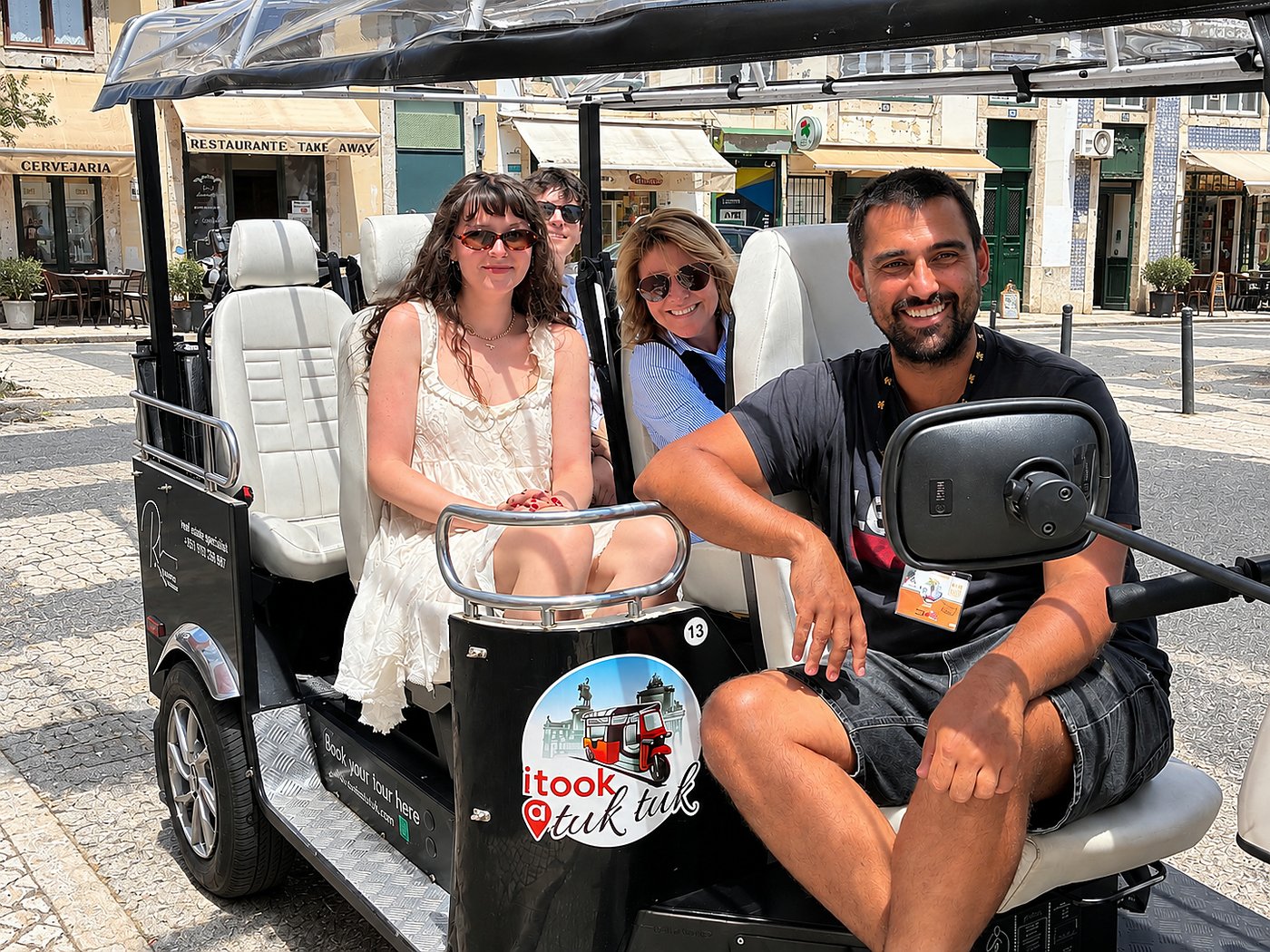 A guide and guests smiling in an I Took a Tuk Tuk electric tuk tuk in Lisbon