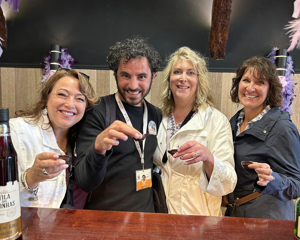 A guide sharing a glass of ginja with four guests around a table in Lisbon