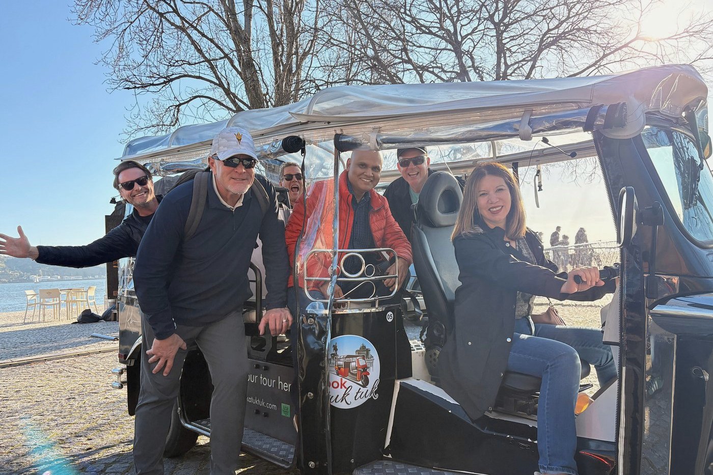 A smiling guide and guests with their private electric tuk tuk by the river in Bel&eacute;m